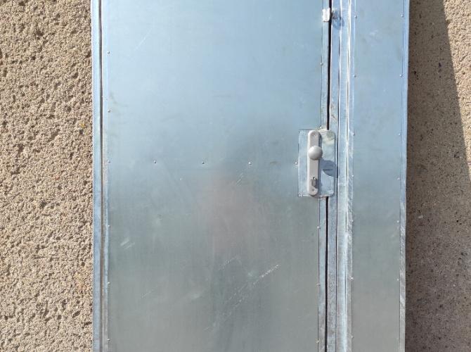 Plechová čelní stěna s dveřmi s odvětrávací mřížkou ve spodní části, povrchová úprava – zinek, zamykání na FAB, kování klika-koule a jedny očka na visací zámek